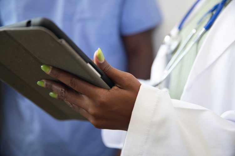 A doctor speaking with a nurse holds a digital tablet.