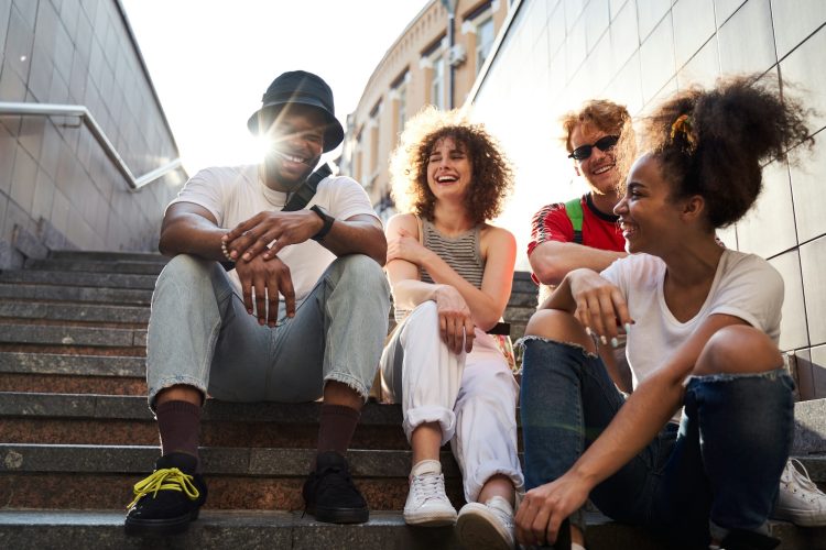 young people — Gen Z friend group sits outside in the city